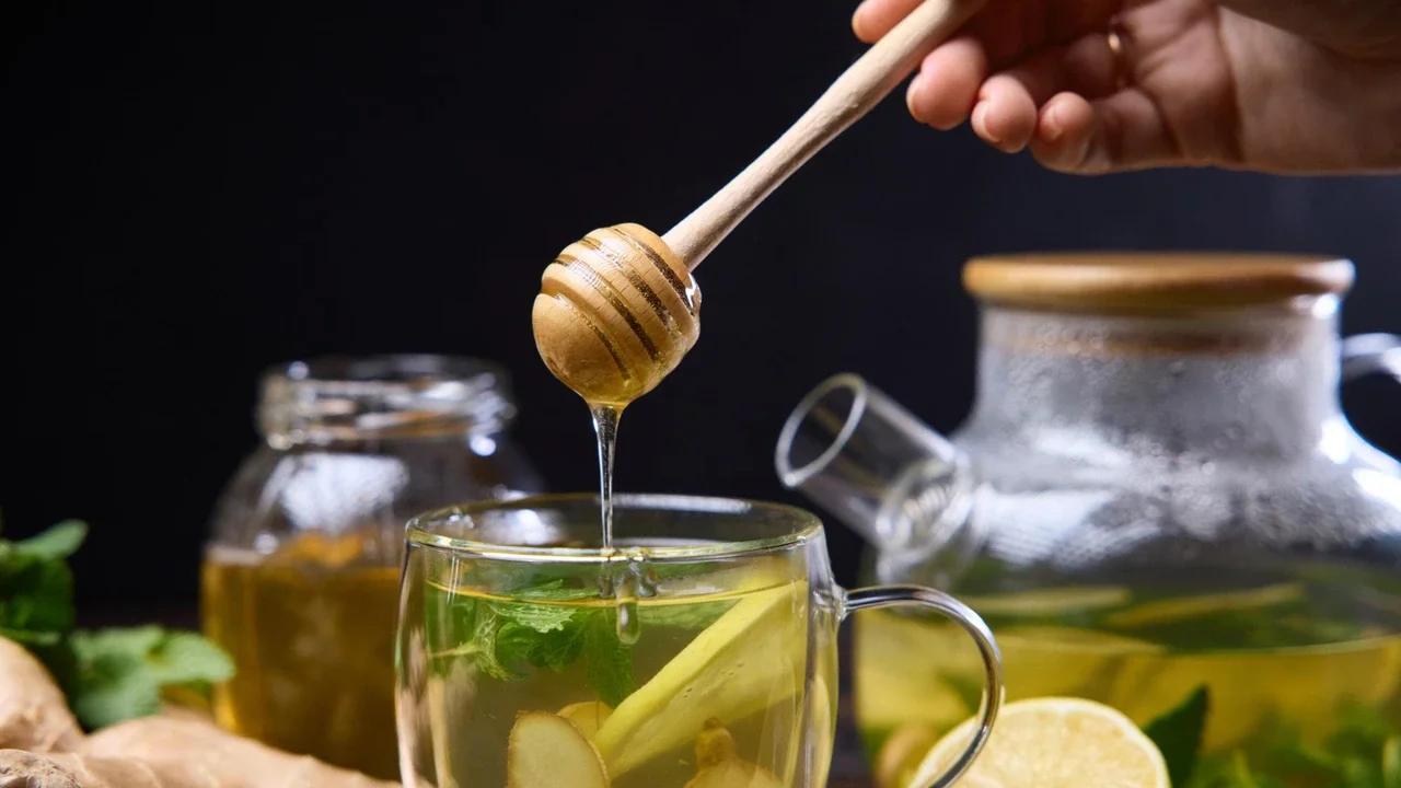 Tisana detox con zenzero e limone in tazza di vetro con miele